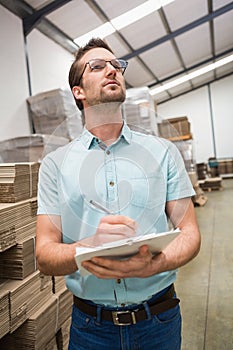 Warehouse worker checking his list on clipboard