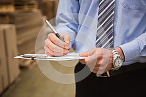 Warehouse worker checking his list on clipboard