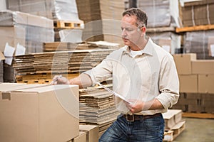 Warehouse worker checking his list on clipboard