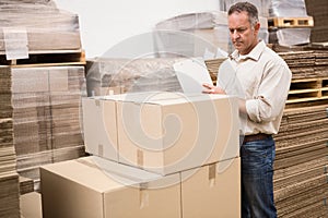 Warehouse worker checking his list on clipboard