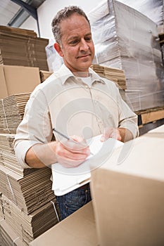 Warehouse worker checking his list on clipboard