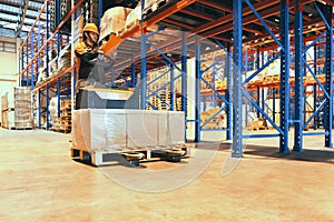 Warehouse worker checking shipment goods on tall shelves at the warehouse storage.