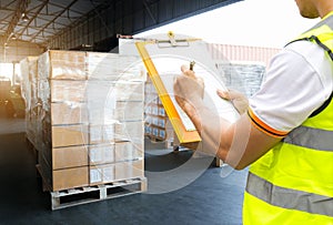 Warehouse worker courier hand holding clipboard inspecting load shipment goods photo