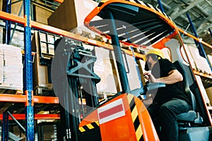 Warehouse worker doing logistics work with forklift loader