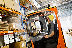 Warehouse worker doing logistics work with forklift loader