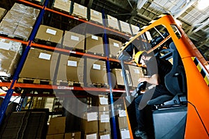 Warehouse worker doing logistics work with forklift loader