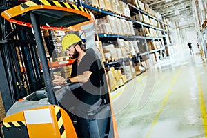 Warehouse worker doing logistics work with forklift loader