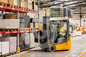 Warehouse worker driving forklift. Warehouse worker preparing products for shipmennt, delivery, checking stock in