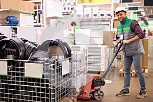 Warehouse worker with fork pallet truck stacker at modern warehouse