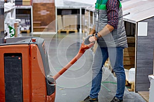 Warehouse worker with fork pallet truck stacker at modern warehouse