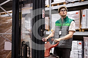 Warehouse worker with hand pallet truck or pallet jack and the shipment in store