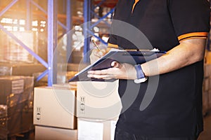 Warehouse Worker Hand Writing on Clipboard His Doing Inventory Management at Storage Warehouse. Check Stock Package Boxes.