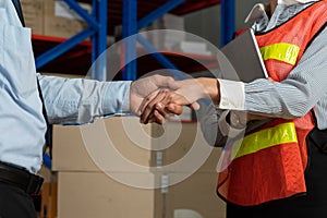 Warehouse worker handshake with manager in storehouse