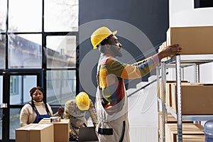 Warehouse worker in hard hat taking carton from shelf