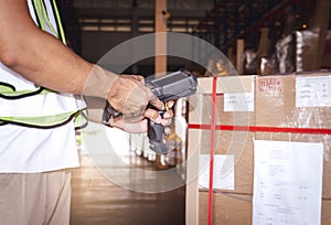 Warehouse worker holding barcode scanner his scanning cargo box. Computer equipment for warehouse inventory management.