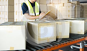 Warehouse worker holding clipboard writing on paper for delivery shipment boxes.