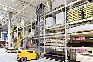 Warehouse worker loading construction materials with forklift