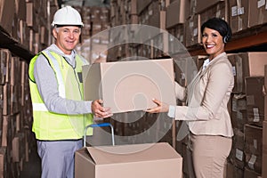 Warehouse worker and manager passing a box