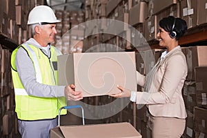 Warehouse worker and manager passing a box