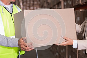 Warehouse worker and manager passing a box