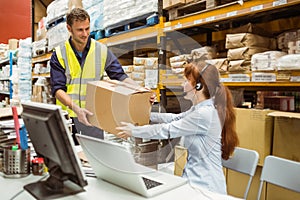 Warehouse worker and manager passing a box
