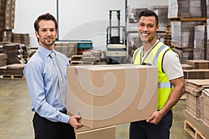 Warehouse worker and manager passing a box