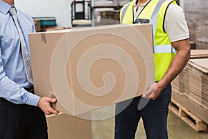 Warehouse worker and manager passing a box