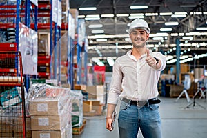 Warehouse worker or manager stand with smiling and show thumbs up to camera in workplace. Concept of professional factory worker