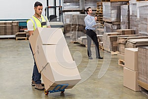 Warehouse worker moving boxes on trolley