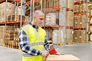 Warehouse worker packing parcel with scotch tape