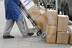 Warehouse worker pulling a hand cart with cardboard boxes