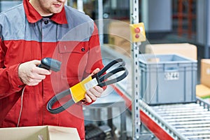 Warehouse worker scanning automobile spare part with laser barcode scanner