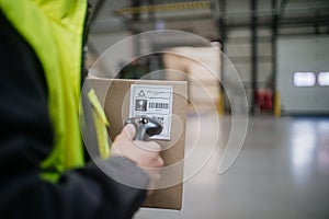 Warehouse worker scanning barcode on cardboard box. Receiving clerk holding scanner checking delivered goods against