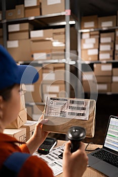 Warehouse worker scanning barcode on parcel using barcode scanner preparing parcels for shipment.