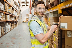 Warehouse worker scanning box while smiling at camera