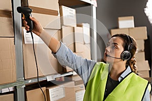 warehouse worker scans a barcode on a box in a large warehouse. brazilian woman worker scans package with barcode
