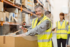 Warehouse worker sealing cardboard boxes for shipping