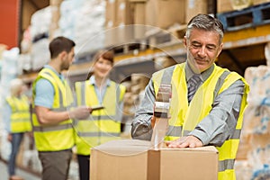 Warehouse worker sealing cardboard boxes for shipping