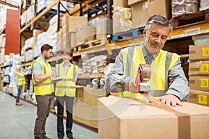 Warehouse worker sealing cardboard boxes for shipping