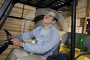 Warehouse Worker Sitting In Forklift And Looking Up