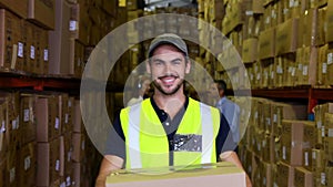 Warehouse worker smiling at camera carrying a box