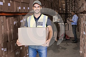 Warehouse worker smiling at camera carrying a box