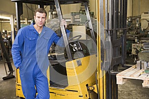 Warehouse worker standing by forklift