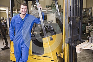 Warehouse worker standing by forklift