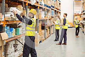 Warehouse worker taking package in the shelf