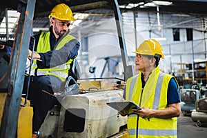 warehouse worker talking with forklift operator in factory