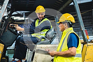 warehouse worker talking with forklift operator in factory