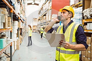 Warehouse worker talking on the phone holding clipboard