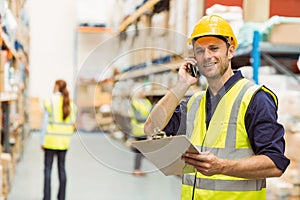 Warehouse worker talking on the phone holding clipboard