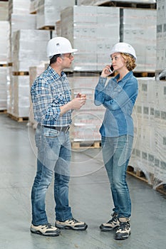 Warehouse worker talking to female supervisor with telephone